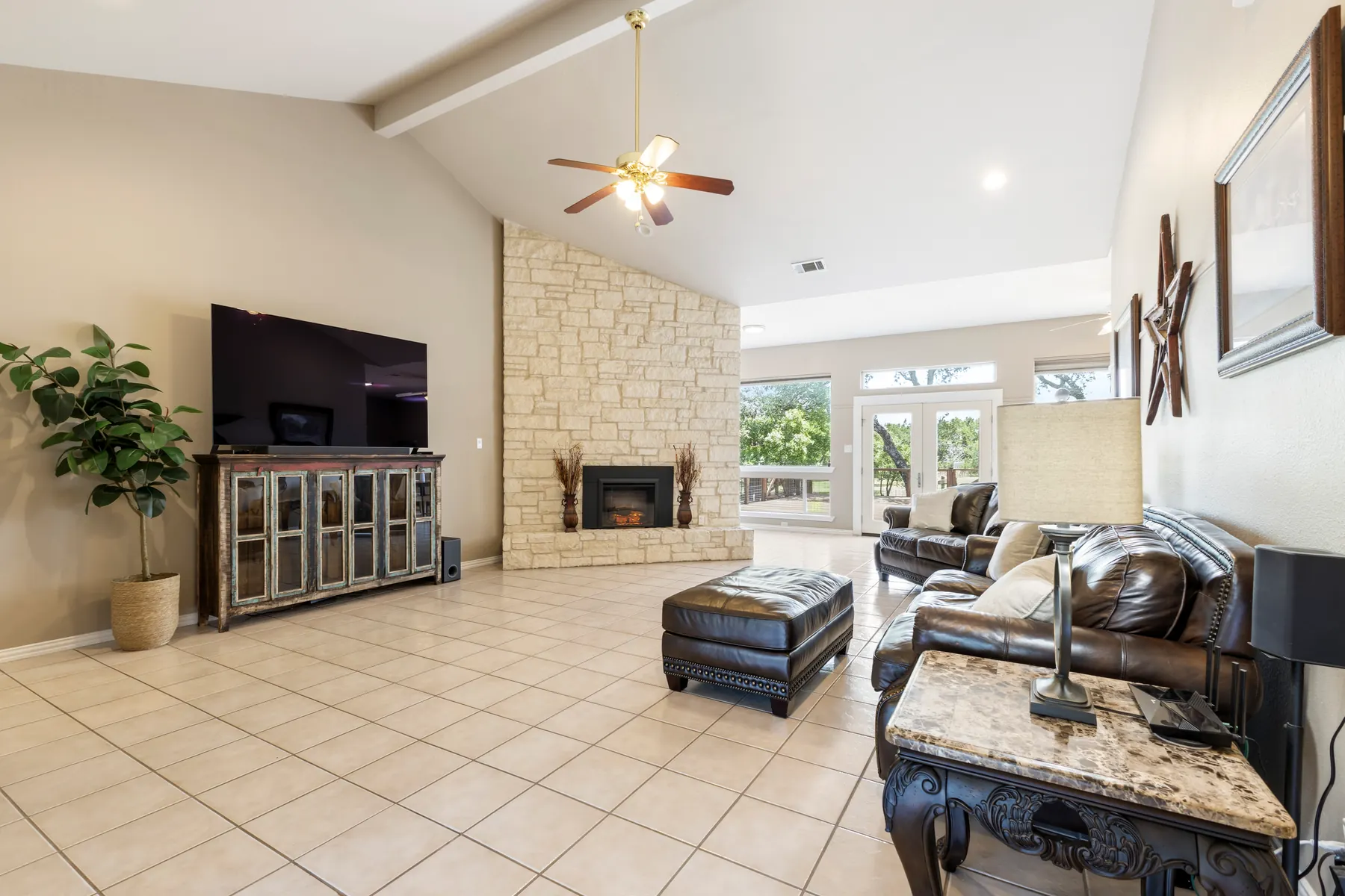 Living room with stone fireplace and backyard views