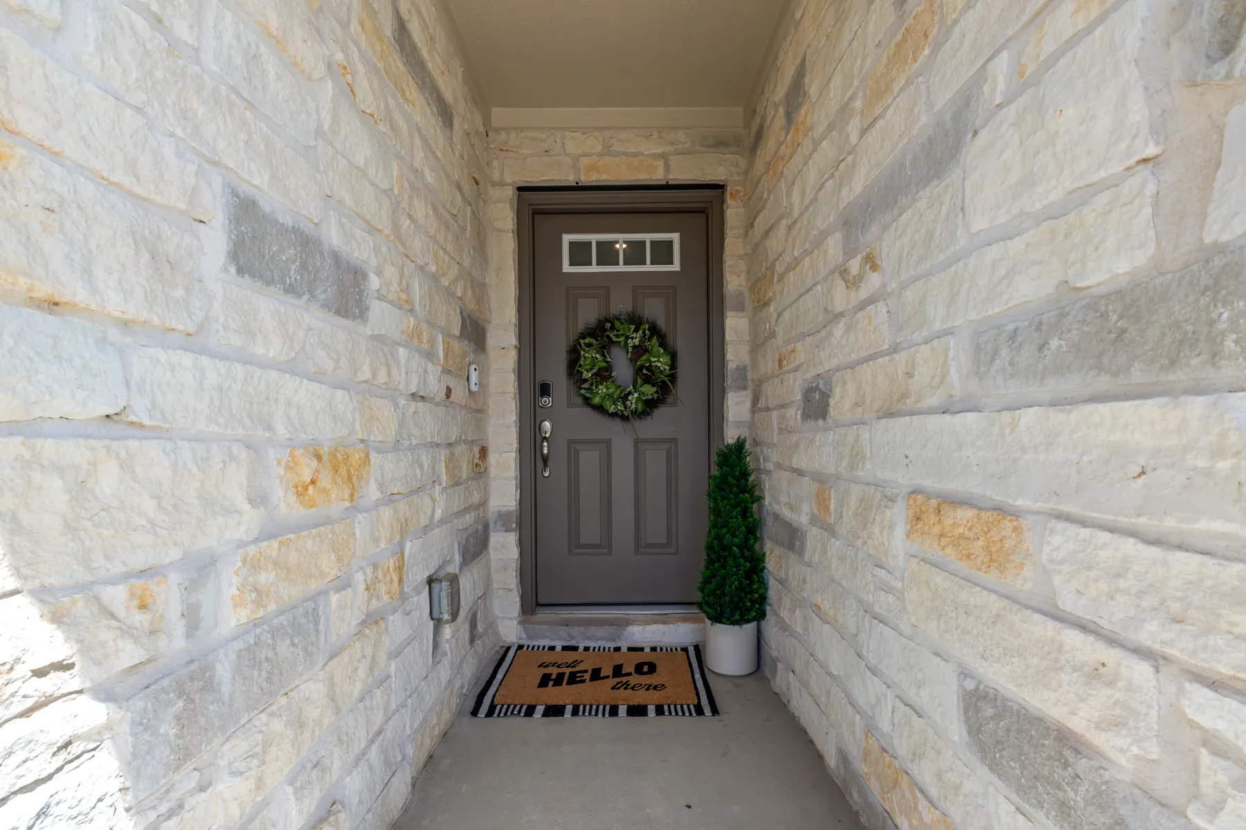 Covered front entry framed by light stone walls